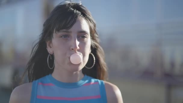 近视黑发女孩用口香糖吹泡泡 — 图库视频影像