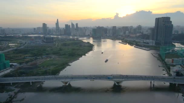 在日落时分飞越位于越南胡志明市下城附近的西贡河大桥 船楼和美丽的金色天空映衬下 — 图库视频影像