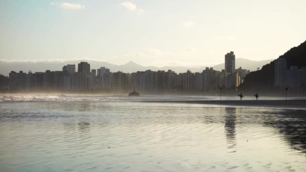 黄昏时 冲浪者在沙滩上走向大海 圣文森特岛的Itarare海滩城市背景 — 图库视频影像