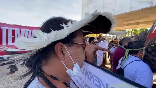 一个举着反对暴力和谋杀的旗帜的人和其他土著人一起站在巴西利亚的最高法院 — 图库视频影像