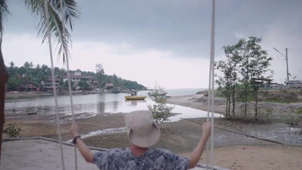 无法辨认的男子在泰国村庄的海滩秋千上荡秋千 缓慢的回旋 — 图库视频影像