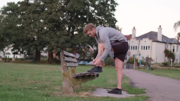 Young Attractive Man Tying His Shoes Bench Sets Run Slow — Stok Video