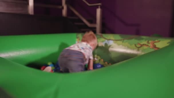 Young Boy Plays Ball Pit Throws Balls Whilst Smiling — Stockvideo