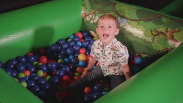 Young Boy Playing Ball Pit Smiling Throwing Balls — Stockvideo