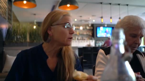 Красивая Зрелая Блондинка Ест Печенье Разговаривает Пожилой Женщиной Ресторане — стоковое видео