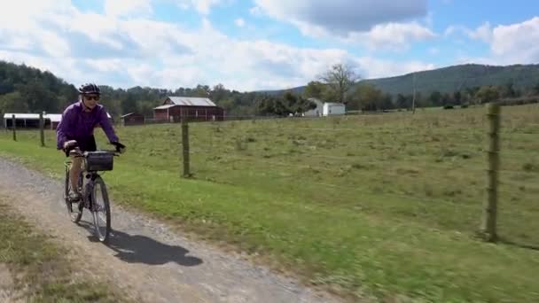 Mature Woman Sunglasses Biking Gravel Road Farm Distance — Vídeo de Stock