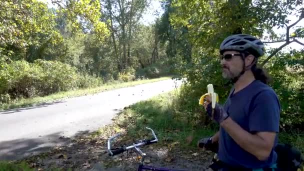 Mature Man Sunglasses Helmet Gloves Next His Bike Eating Banana — Stockvideo