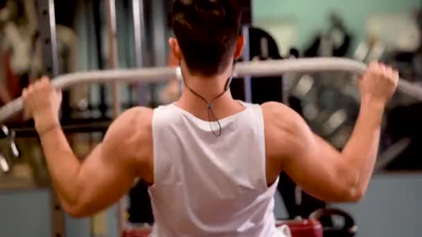 Rear extreme closeup of young bodybuilder doing lat pulldowns on a machine.