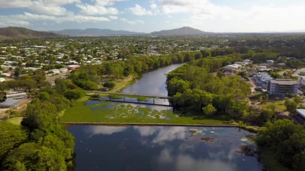清晨时分 无人机在一条平静的反光河上飞行 上面有一道堤坝墙 山谷和一座脚下的桥 周围都是房屋 位于澳大利亚汤斯维尔罗斯河 — 图库视频影像