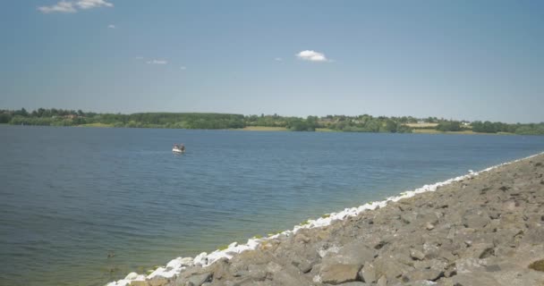 Sunny Shot Reservoir Boat Sailing Distance Alongside Rocky Border Sand — Stockvideo