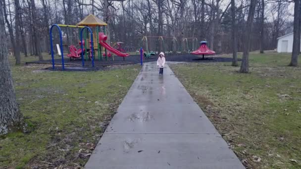 Young Girl Walks Camera Playground Background Concrete Sidewalk Rain Puffy — Stock videók