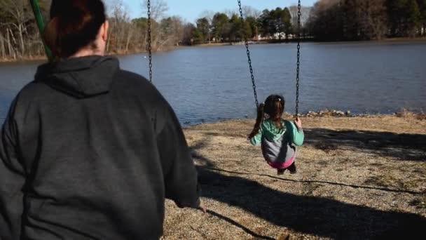 Mother Pushing Young Daughter Swingset Park Lake — Stok video