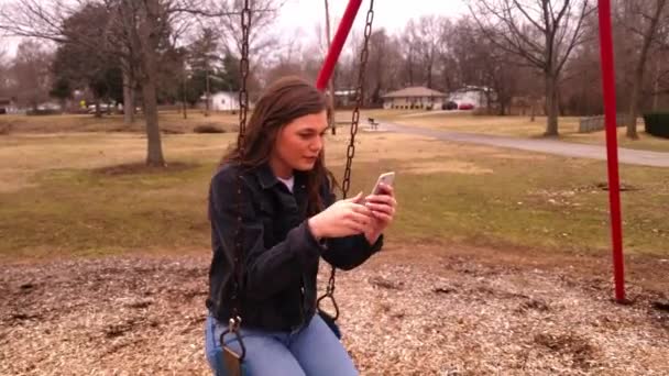 Видео Великолепного Студента Сидящего Качелях Используя Свой Мобильный Телефон Зеркало — стоковое видео