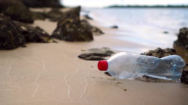 Plastic Bottle Sits Motionless Amongst Rocks Small Sandy Beach Water — Stockvideo