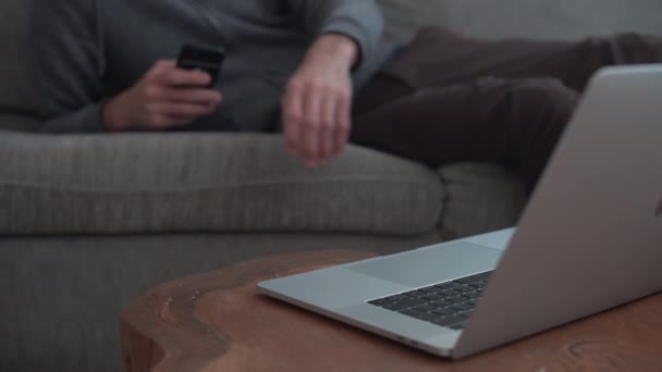 Man Lying Sofa Home Uses Mobile Phone Types Laptop — Stock videók