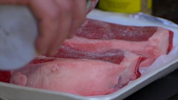 Hand Pours Salt All Raw Rib Eye Steak — стоковое видео