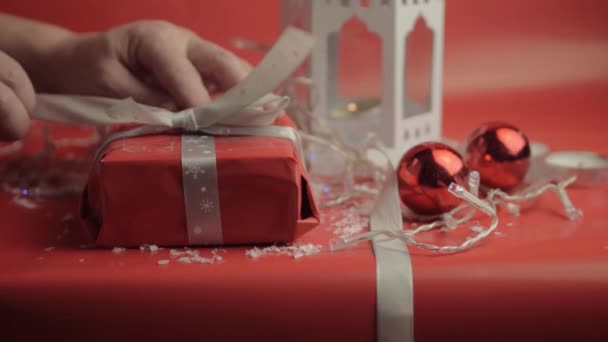 Ξετυλίγοντας Χριστουγεννιάτικο Δώρο Κορδέλα Και Κόκκινο Χαρτί Κόκκινο Φόντο Και — Αρχείο Βίντεο