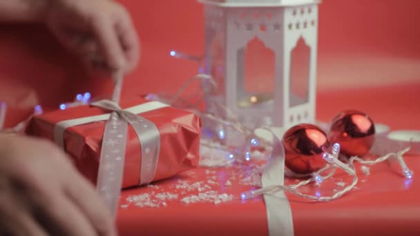 Обертывание Рождественский Подарок Лентой Красной Бумагой Красным Фоном Безделушками — стоковое видео