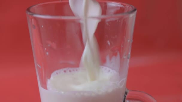 Kırmızı Arka Planda Bir Bardağa Süt Dökmek — Stok video