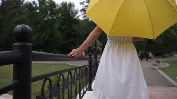 Woman White Dress Yellow Umbrella Walks Smiles Handheld Slomo — Stockvideo