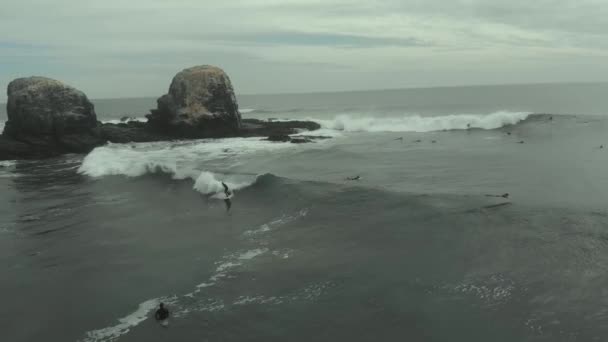 Aerial Pro Surfer Riding Wave Next Giant Rocks Cold Cloudy — Vídeo de Stock