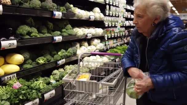 Starsza Kobieta Spożywczaku Wkłada Brokuły Plastikowej Torby — Wideo stockowe