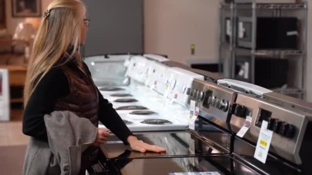 Pretty Mature Blonde Woman Turning Knobs Stove Kitchen Appliance Store — Vídeos de Stock