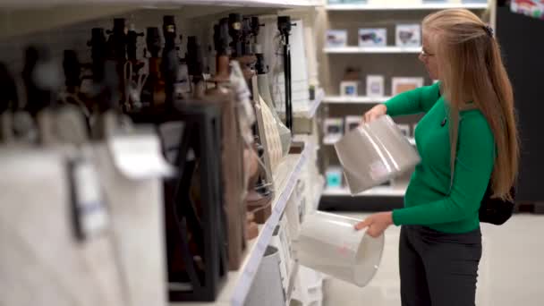 Pretty Blonde Mature Woman Comparing Lamp Shades Store Display — Stock video