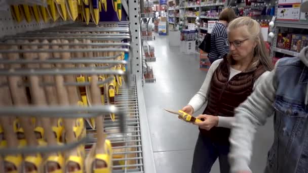 Pretty Mature Blonde Woman Looks Paint Brushes Hardware Store — Vídeo de Stock