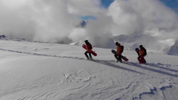 Drone Three Snowboarders Sideways While Walking Summit Big Mountain — Vídeo de Stock