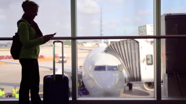 Silhouette Woman Smiling Luggage Smartphone Blurry Plane Window — Vídeo de stock
