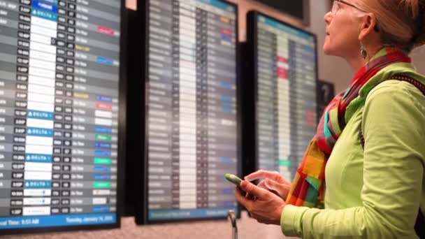 Closeup Woman Holding Smartphone Looking Her Flight Flight Information Display — Stockvideo