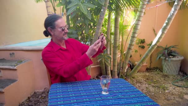 Mature Man Wearing Guayabera Shirt Touches Smartphone Garden Table Laptop — Stok Video