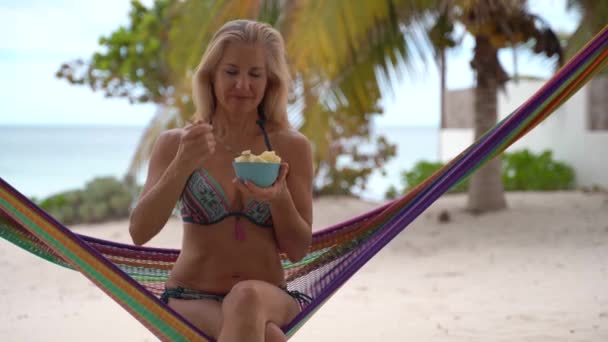 Pretty Mature Woman Sunglasses Bikini Hammock Eating Pineapple Looking Unbelievably — Vídeos de Stock