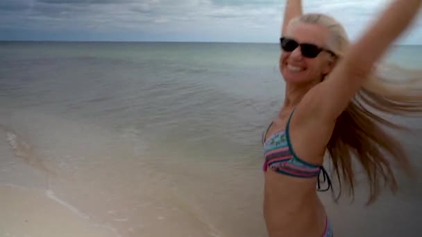 Playful Blonde Mature Woman Sunglasses Bikini Running Beach Looking Back — Video