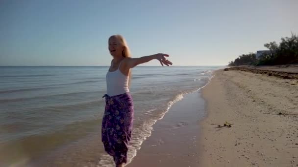 Slow Motion Joyous Mature Woman Backlit Splashing Water Beach Sunrise — стоковое видео