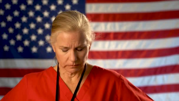 Средний Плотный Портрет Медсестры Выглядящей Взволнованной Грустной Американским Флагом Позади — стоковое видео