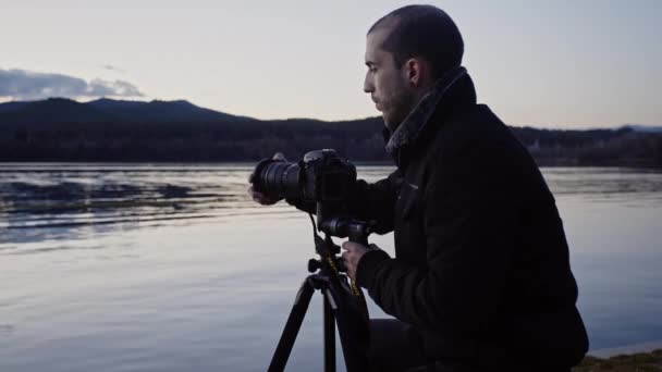 Caucasian Man Adds Filter Camera Lens Attached Tripod Calm Lake — Wideo stockowe