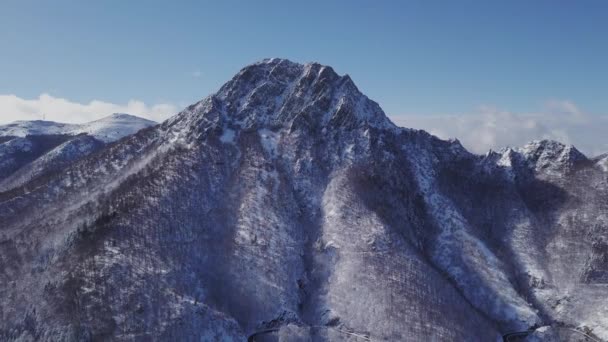 들쭉날쭉 몽테니 산맥의 과맑고 하늘을 배경으로 눈덮인 산비탈쪽 도로를 당기는 — 비디오