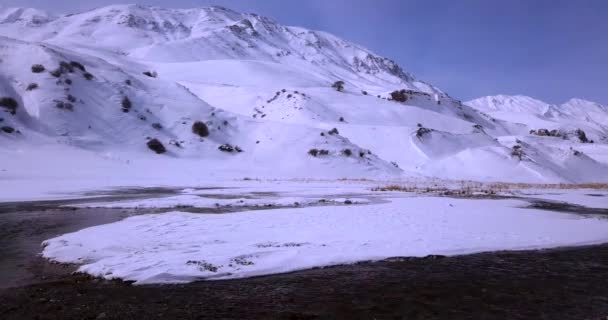 Fly Frozen Icy River Stream Flow White Snow Covered Mountain — Video