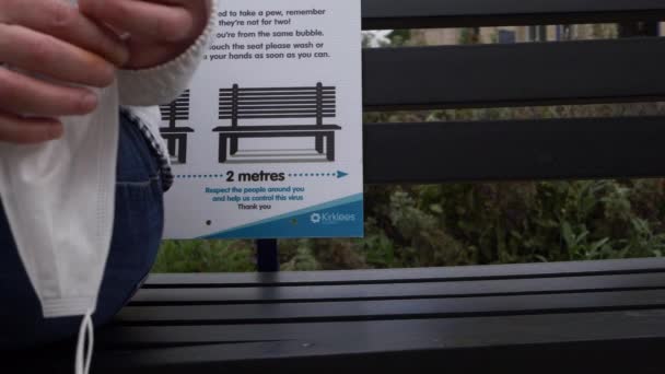 Person Sitting Bench Holding Face Mask Close Shot — Stok Video