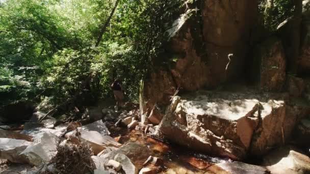 Άνθρωπος Σκαρφαλώνει Πάνω Από Τους Βράχους Στους Καταρράκτες Του Ποταμού — Αρχείο Βίντεο