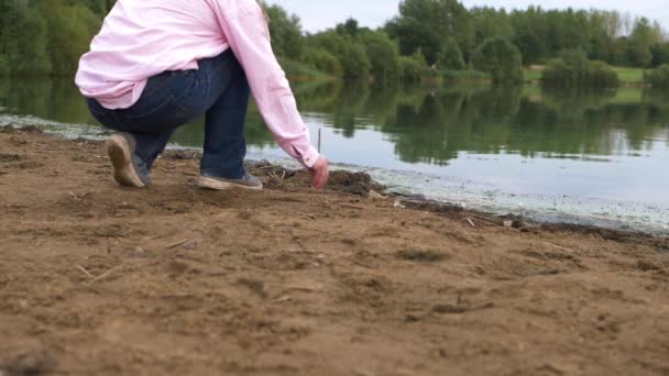 Samotny Człowiek Bazgroły Złocistym Piasku Kijem Nad Jeziorem Szeroki Krajobraz — Wideo stockowe