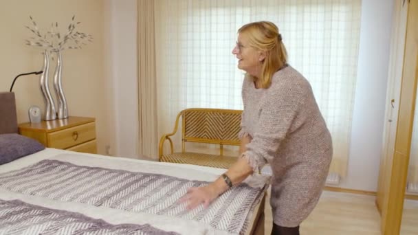 Older Woman Making Her Bed Looks Relaxed — Vídeo de Stock