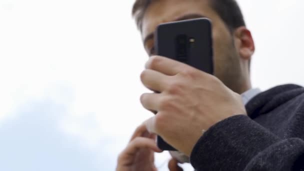 Man Looking Mobile Putting Heladphones White Sky Background — 图库视频影像