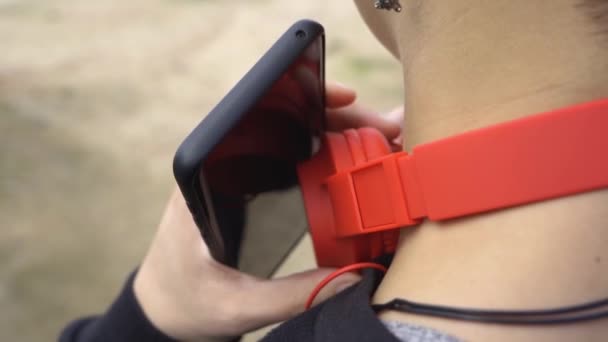 Woman Puts Headphones Looks Touches Mobile Screen — Vídeo de Stock