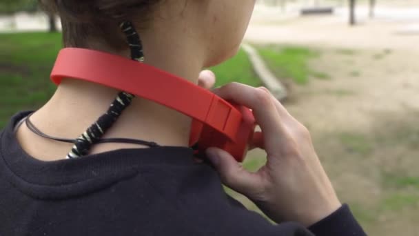 Woman Watches Mobile Puts Red Headphones Walks — ストック動画