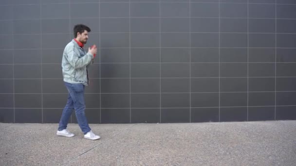 Man Puts Red Headphones Walks While Looking Red Cell Phone — Αρχείο Βίντεο