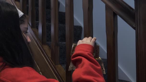 階段のスピンドルに金の葉のデザインと若い女の子のティーネージャースティックダブルクリスマス弓 ロックオフ — ストック動画