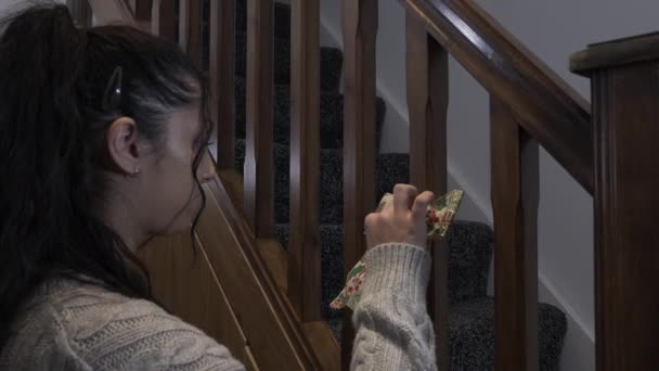 十代の女性は 階段のスピンドルにホリーとミステリーデザインとダブルクリスマスの弓を配置します — ストック動画
